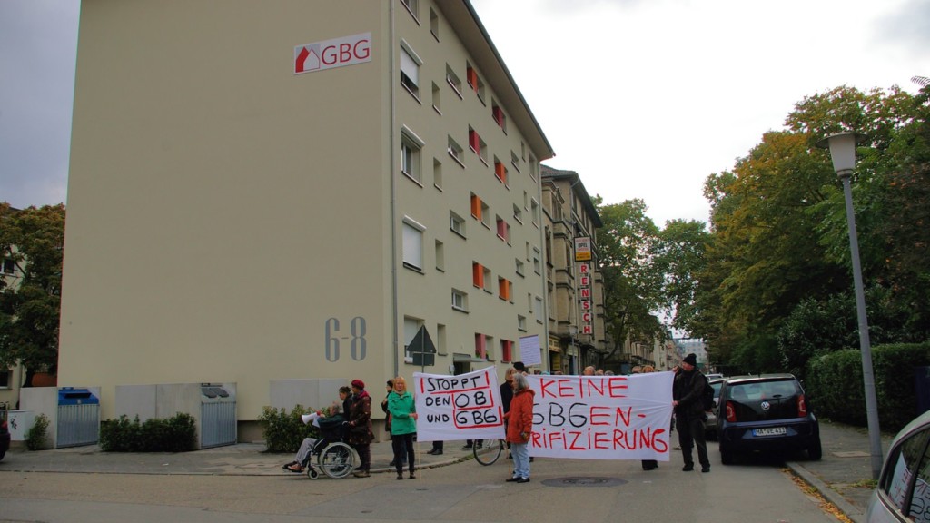 Wie ein Damoklesschwert hängt das GBG-Logo über den demonstrierenden Mietern | Foto: M. Schülke